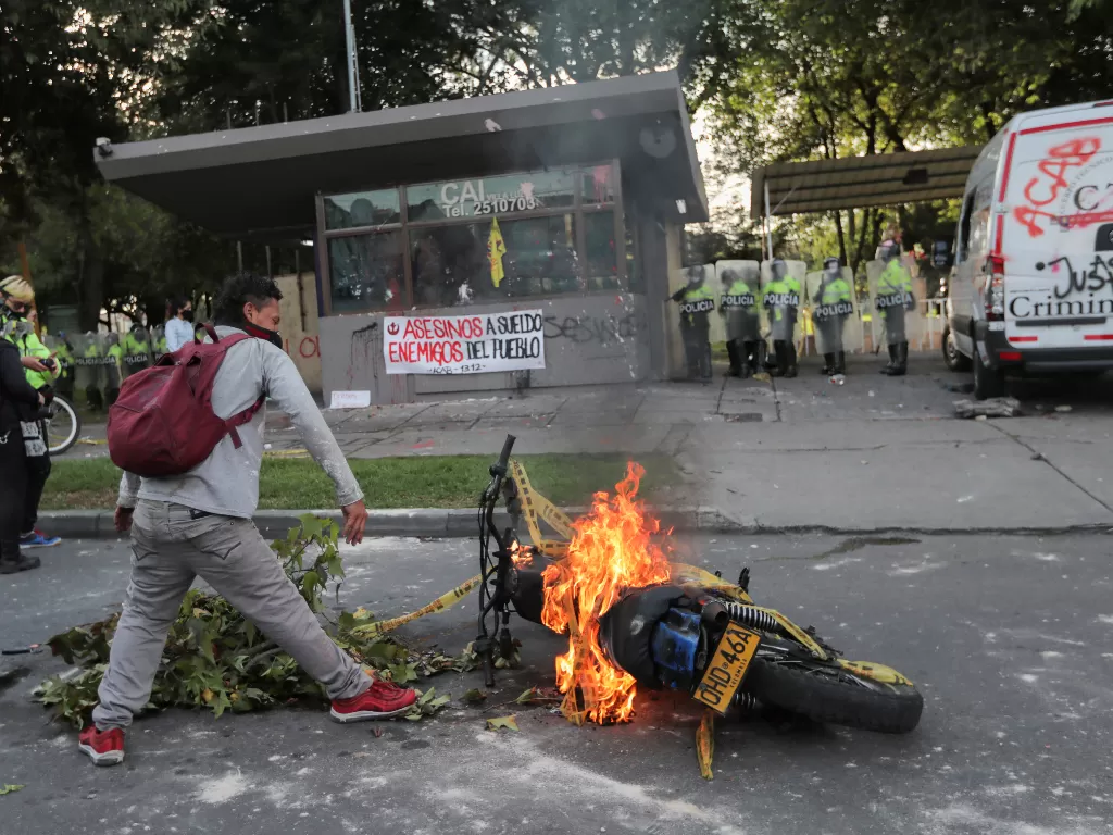 Seorang demonstran berdiri di dekat sepeda motor yang terbakar (REUTERS/Luisa Gonzalez)