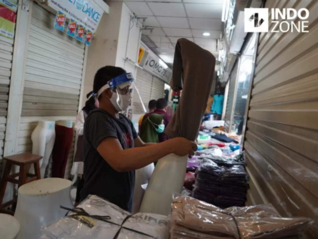 Pedagang memakai masker dan face shield saat merapikan dagangannya di Pasar Tanah Abang Blok A, Jakarta, Senin (15/6/2020). (INDOZONE/Arya Manggala)