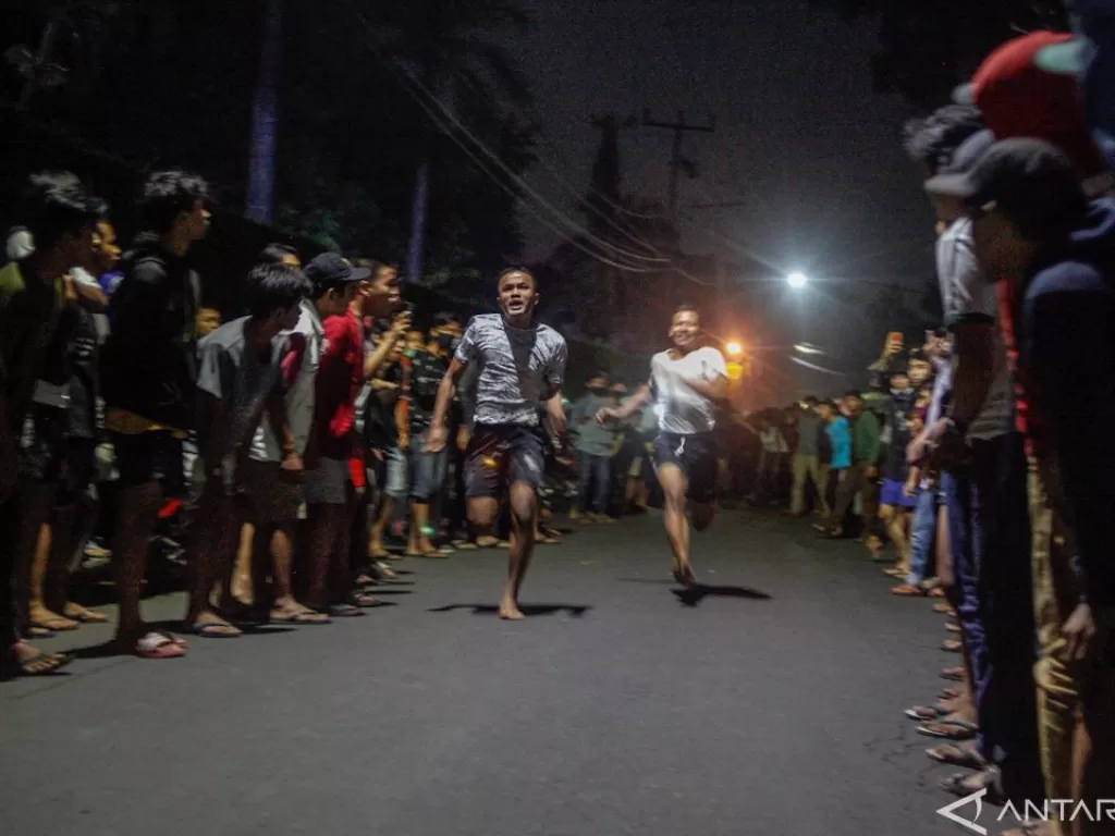 Dua remaja berlomba lari 100 meter di Jalan Raya Ciri Mekar, Cibinong, Kabupaten Bogor, Sabtu dini hari (12/9/2020). (Antara/Yulius Satria Wijaya)
