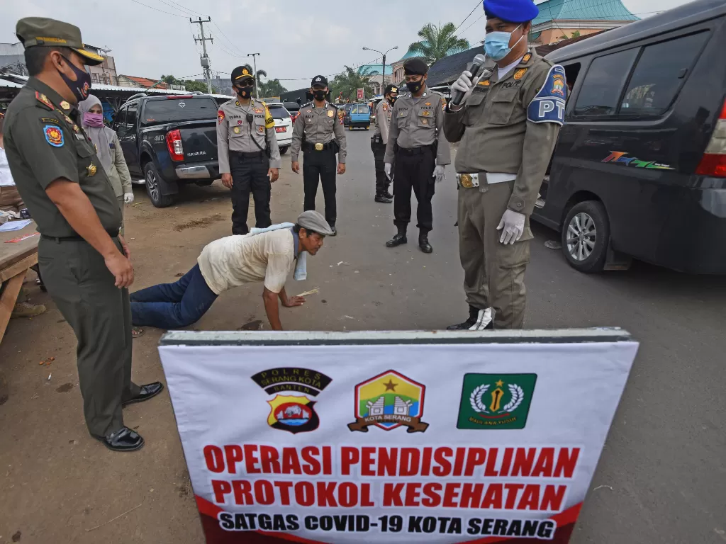 Personel Polisi Pamong Praja disaksikan anggota Polri memberi hukuman push-up kepada warga yang tidak memakai masker saat Operasi Pendisiplinan Protokol Kesehatan di Jalan Cimuncang, Serang, Banten, Selasa (15/9/2020). ANTARA FOTO/Asep Fathulrahman