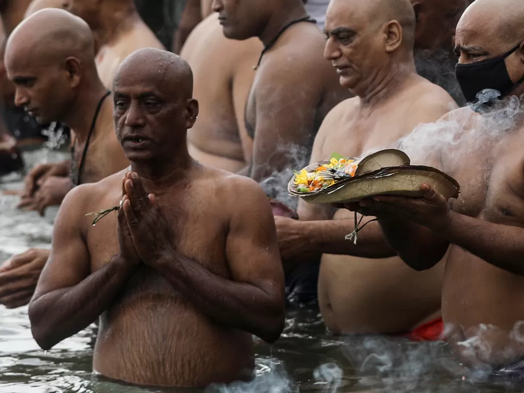 Para penyembah berdoa saat mereka berenang di danau untuk menghormati jiwa leluhur mereka yang telah meninggal pada hari keberuntungan di Mahalaya (REUTERS/Francis Mascarenhas)