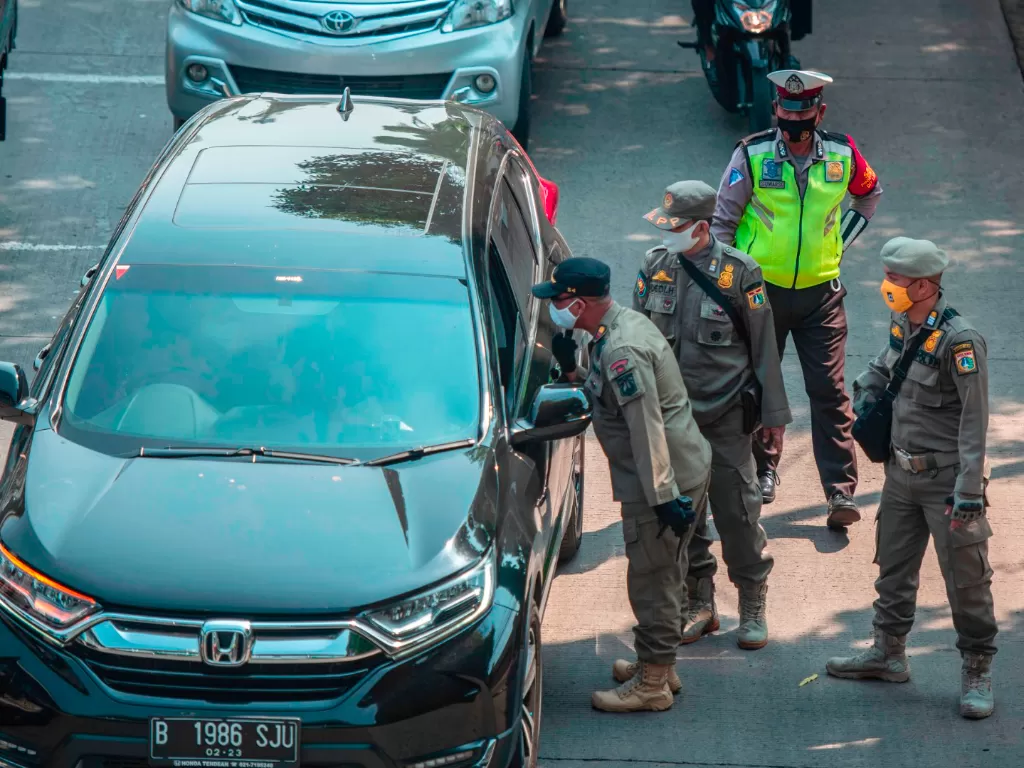 Anggota Satpol PP dan Polisi Lalu Lintas memberhentikan sopir mobil tidak bermasker dalam Operasi Yustisi Protokol COVID-19 di kawasan Jati Padang, Jakarta, Kamis (17/9/2020). (ANTARA FOTO/Aprillio Akbar)
