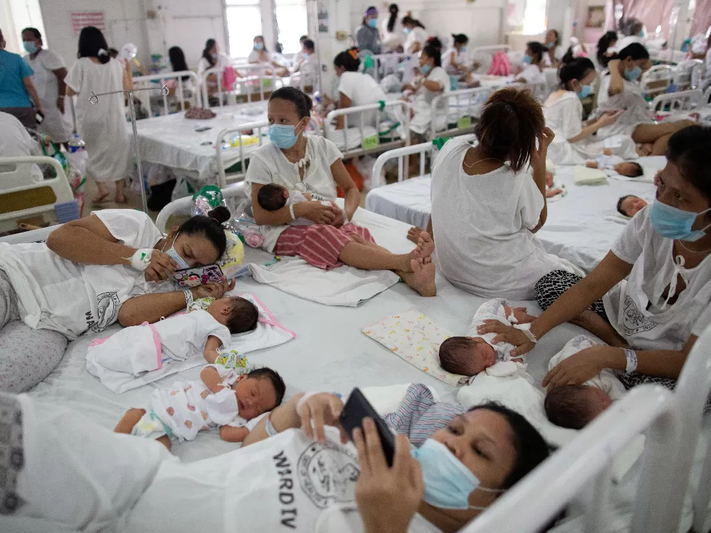 Para ibu yang mengenakan masker beristirahat dengan bayi mereka yang baru lahir di tempat tidur bersama di dalam bangsal bersalin Rumah Sakit Memorial Dr. Jose Fabella yang dikelola pemerintah (REUTERS/Eloisa Lopez)