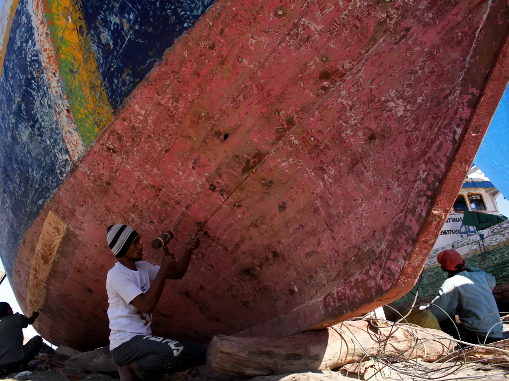 Pekerja menyelesaikan perbaikan badan kapal nelayan di Pantai Batu-Batu (ANTARA FOTO/Arnas Padda)
