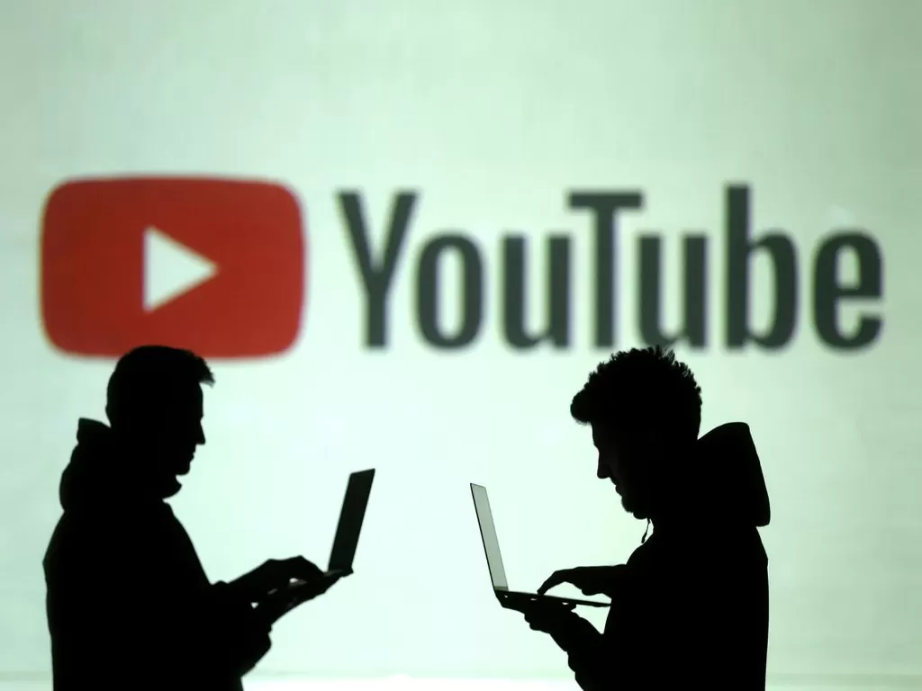 Ilustrasi dua orang sedang berada di depan logo YouTube (photo/REUTERS/Dado Ruvic)