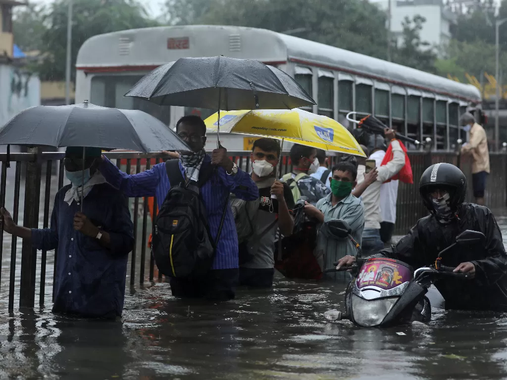 Orang-orang mengarungi jalan yang tergenang air setelah hujan lebat di Mumbai, India (REUTERS/Francis Mascarenhas)