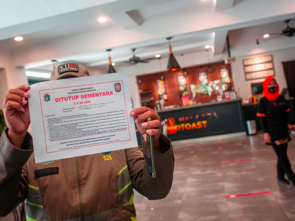 Petugas Satpol PP menutup restoran yang menyediakan layanan makan di tempat saat razia PSBB Jakarta di kawasan Sunter Agung, Jakarta, Kamis (24/9/2020). ANTARA FOTO/Aprillio Akbar