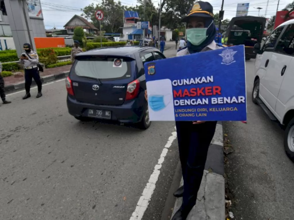 Petugas memegang papan imbauan saat menggelar operasi yustisi protokol kesehatan di Palu, Sulawesi Tengah, Kamis (24/9/2020). (ANTARA FOTO/Mohamad Hamzah)