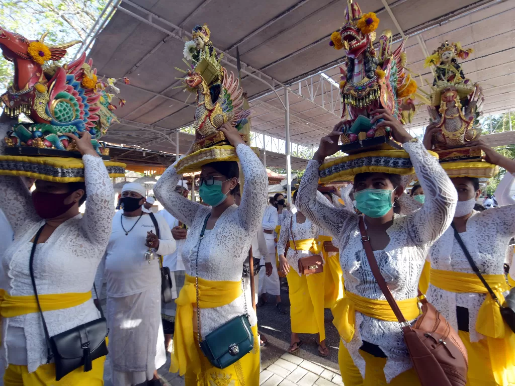Umat Hindu menggunakan masker saat membawa benda-benda sakral dalam ritual menjelang Hari Raya Kuningan di Pura Sakenan (ANTARA FOTO/Nyoman Hendra Wibowo)