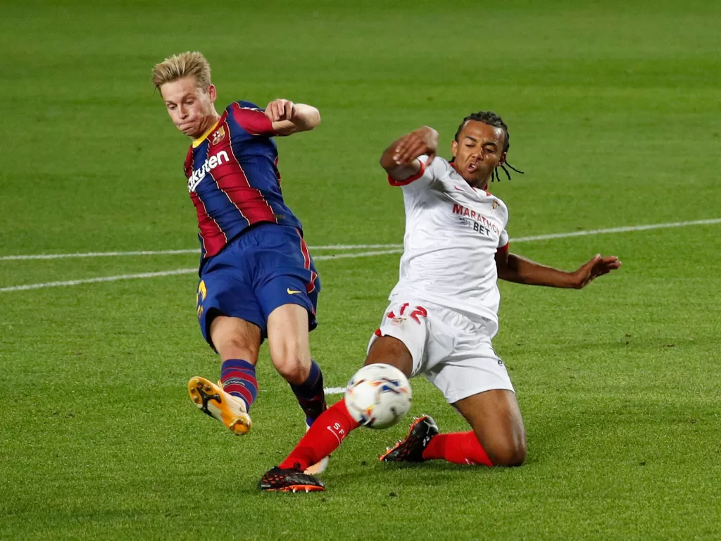 Frenkie de Jong dari Barcelona beraksi dengan pemain Sevilla, Jules Kounde (REUTERS/Albert Gea)