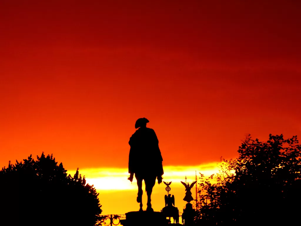 Matahari terbenam di belakang patung Berkuda Frederick Agung di jalan raya Unter den Linden (REUTERS/Joachim Herrmann)
