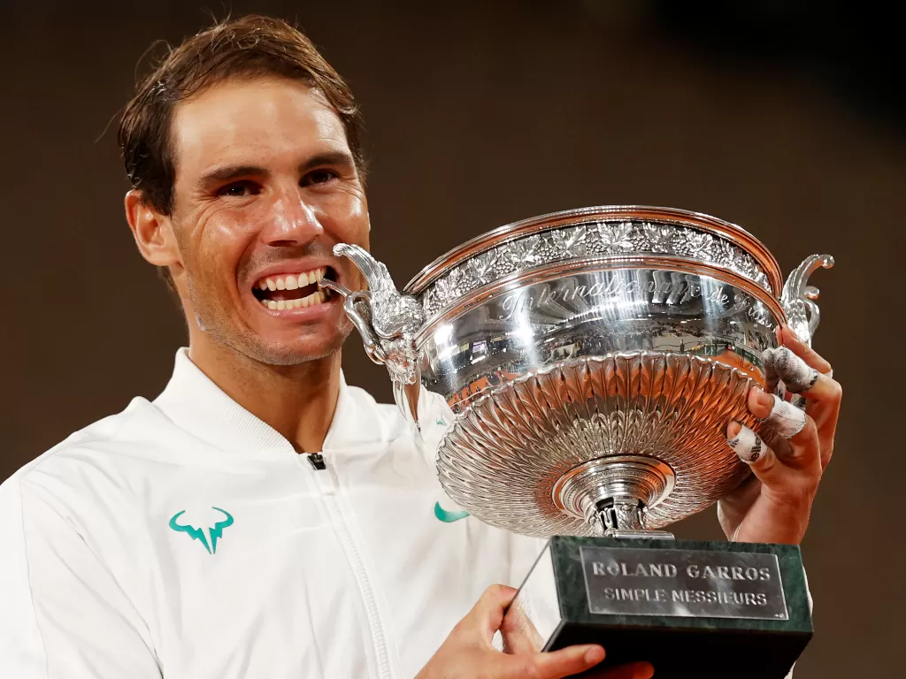 Rafael Nadal dari Spanyol merayakan dengan trofi tersebut setelah memenangkan final Prancis Terbuka melawan Novak Djokovic dari Serbia (REUTERS/Christian Hartmann)