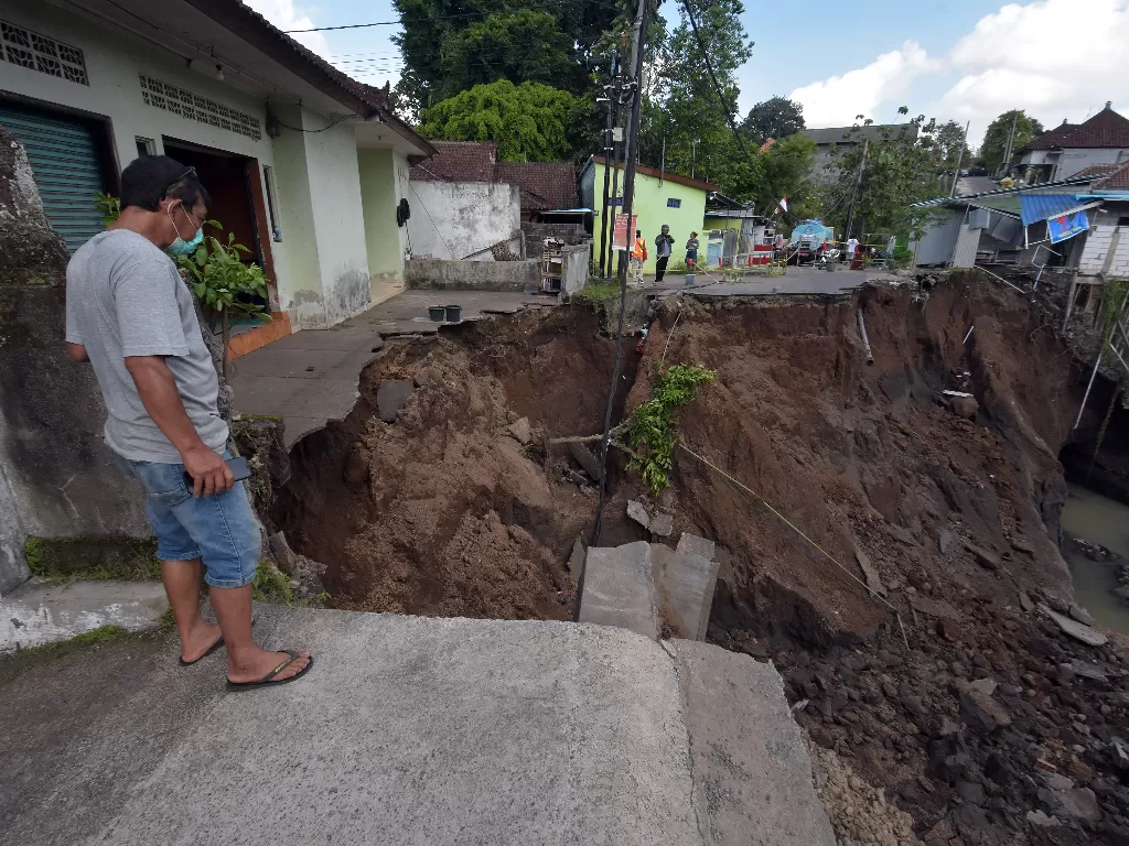 Warga melihat kondisi jalan yang putus akibat cuaca ekstrem yang terjadi di Lingkungan Sanggulan, Desa Banjar Anyar, Tabanan, Minggu (11/10/2020). ANTARA FOTO/Nyoman Hendra Wibowo