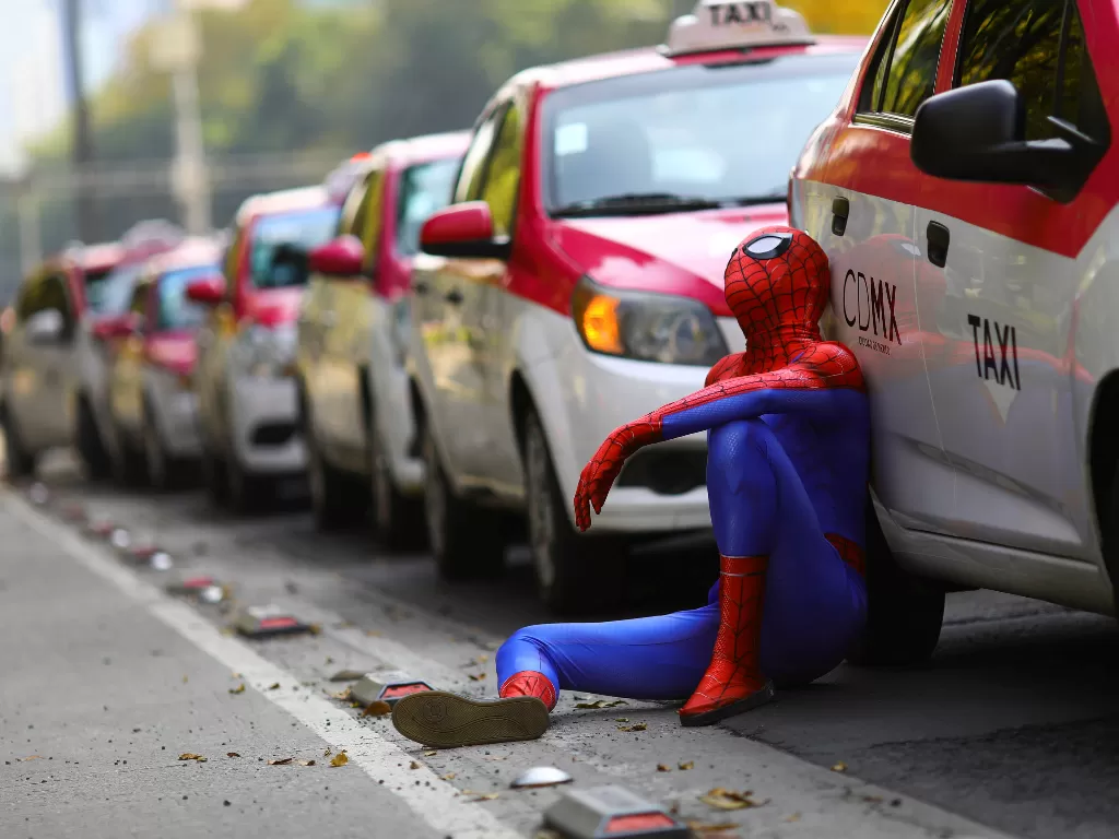 Seseorang yang berpakaian seperti Spider-Man duduk di samping taksi saat pengemudi taksi mengadakan protes terhadap aplikasi pemanggil taksi seperti Uber, Cabify dan Didi di monumen Angel de la Independencia, di Mexico City, Meksiko (REUTERS/Edgard Garrid