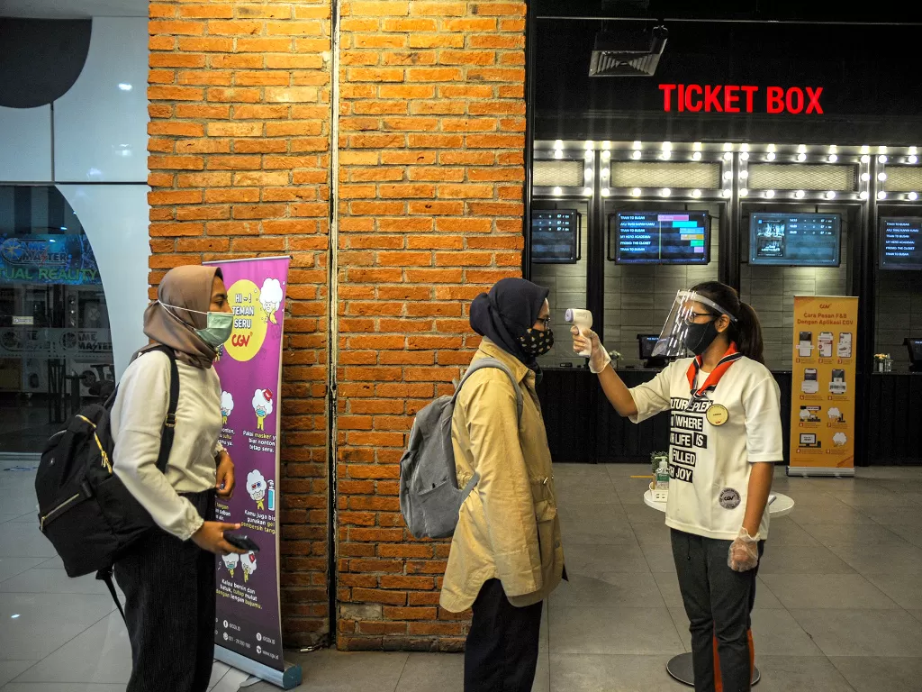 Petugas memeriksa suhu tubuh pengunjung yang akan menonton film di salah satu bioskop di Kota Bandung, Jawa Barat, Jumat (9/10/2020). (Photo/ANTARA FOTO/Raisan Al Farisi)