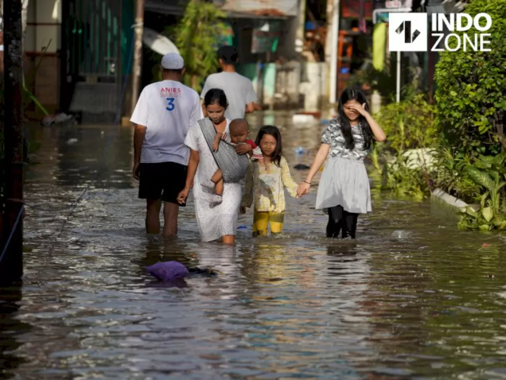 Warga melintasi banjir di kawasan Karet Tengsin, Tanah Abang, Jakarta Pusat, Selasa (25/2/2020). (INDOZONE/Arya Manggala)