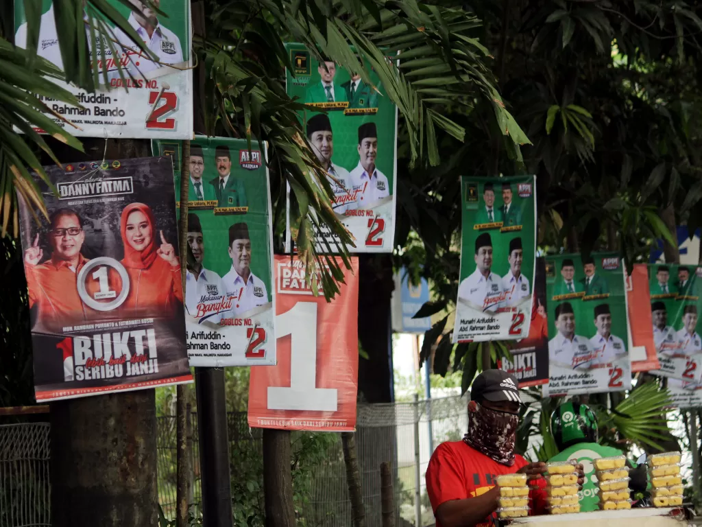 Pedagang kaki lima menjajakan dagangannya di dekat alat peraga kampanye (APK) yang terpasang di pohon dan tiang listrik di Makassar (ANTARA FOTO/Arnas Padda)
