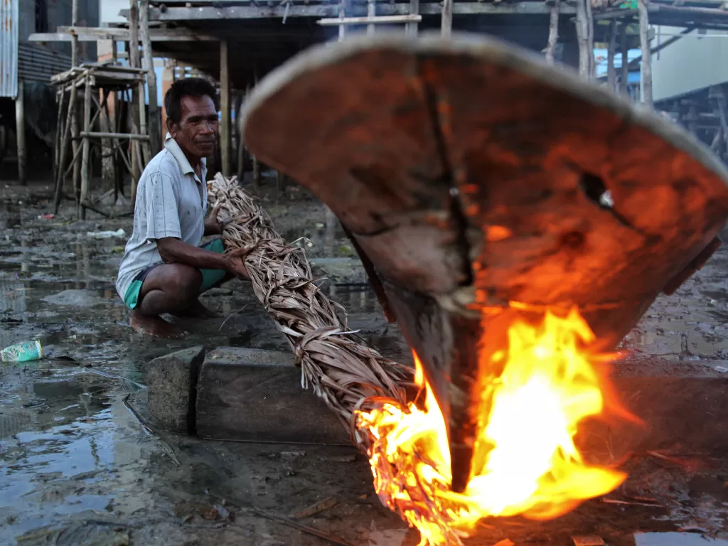 Nelayan Suku Bajo membakar lumut dan kotoran pada perahu dengan daun kelapa kering (ANTARA FOTO/Jojon)