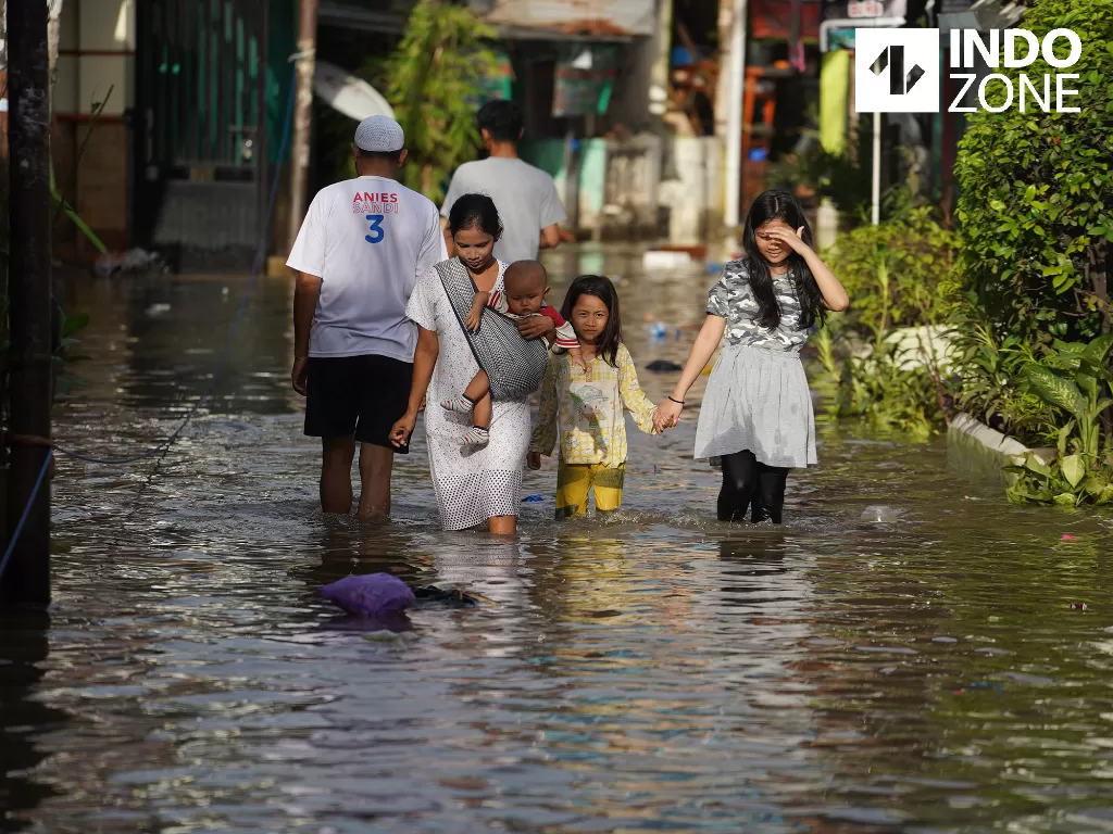 Warga melintasi banjir di kawasan Karet Tengsin, Tanah Abang, Jakarta Pusat, Selasa (25/2/2020). (INDOZONE/Arya Manggala)