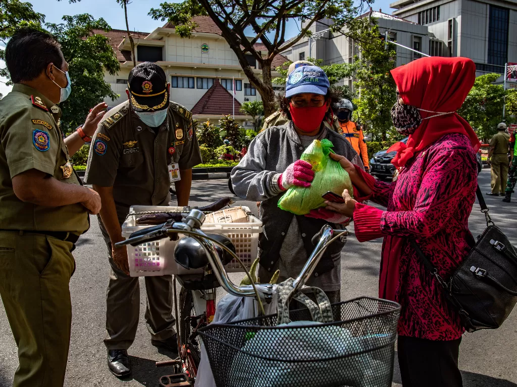Petugas penegak protokol kesehatan Kota Semarang memberikan sembako gratis kepada warga yang mematuhi protokol kesehatan (ANTARA FOTO/Aji Styawan)