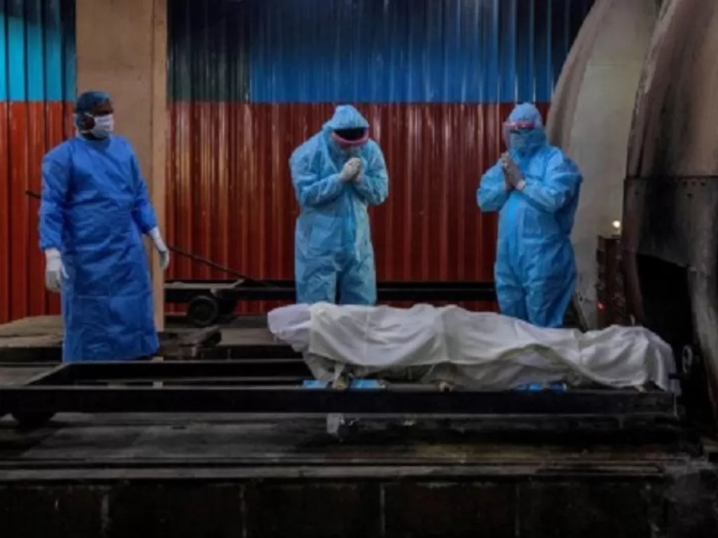 Kerabat berdoa sebelum kremasi seorang wanita, yang meninggal karena penyakit virus corona (Covid-19) di sebuah krematorium di New Delhi, India, Rabu (8/7/2020). (REUTERS/Danish Siddiqui)
