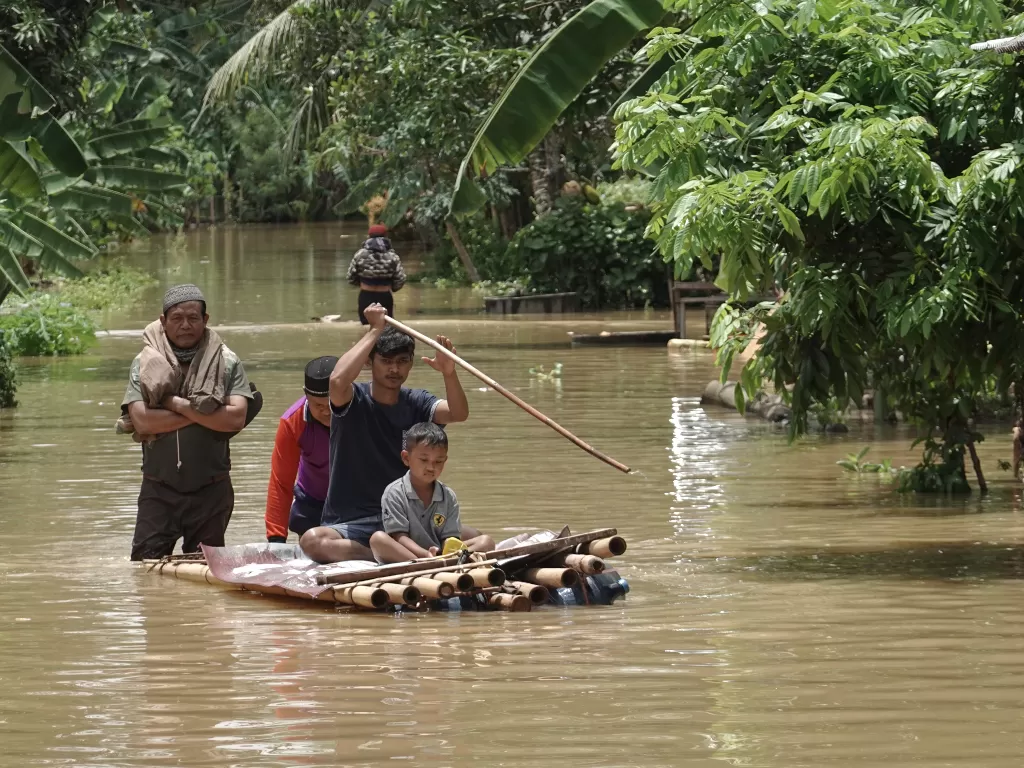 Warga menggunakan rakit darurat untuk melakukan evakuasi dari rumah yang terendam banjir di Desa Gentasari, Kroya, Cilacap, Jawa Tengah, Selasa (27/10/2020). ANTARA FOTO/Idhad Zakaria