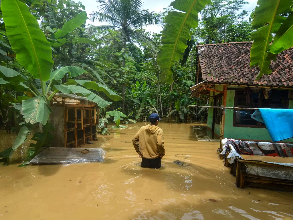 Warga menerobos genangan air saat masuk kedalam rumahnya pascabanjir di Desa Sindangrasa (ANTARA FOTO/Adeng Bustomi)