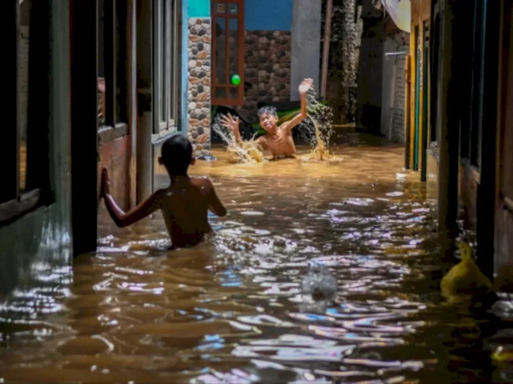 Warga bermain ketika banjir di Kebon Pala, Jatinegara. (ANTARA/Galih Pradipta)