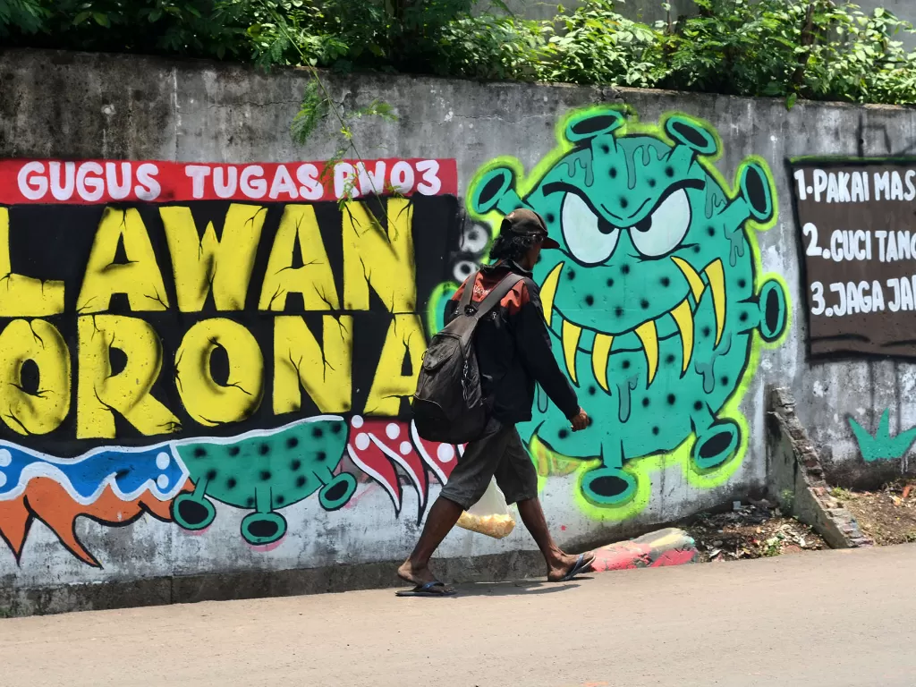 Warga melintas di depan mural berisi ajakan melawan corona di Jalan Pahlawan Komarudin RW 03, Cakung Barat, Jakarta Timur, Sabtu (17/10/20). (Photo/Ilustrasi/ANTARA FOTO/Suwandy)