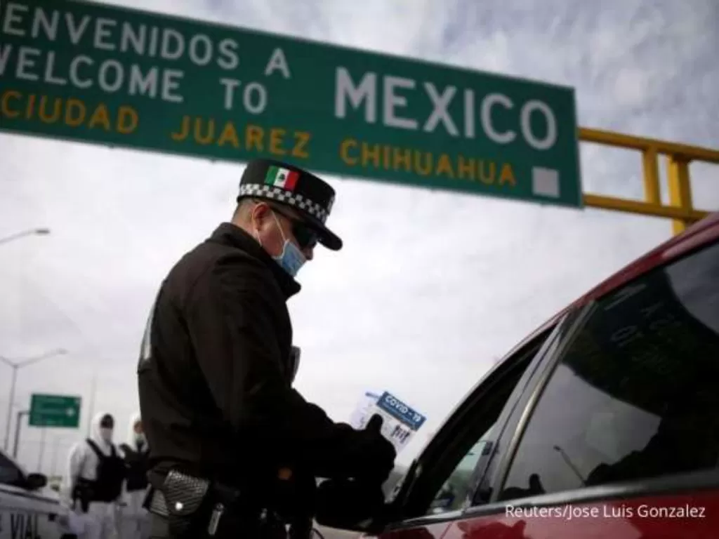 Ilustrasi petugas memberikan arahan terkait protokol kesehatan Covid-19 kepada warga yang memasuki kawasan Meksiko. (REUTERS/Jose Luis Gonzalez)