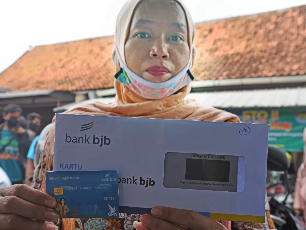 Pelaku usaha mikro memperlihatkan kartu ATM saat pencairan bantuan stimulus di halaman Kantor Disperindag Kota Serang, di Serang, Banten, Senin (2/11/2020). ANTARA FOTO/Asep Fathulrahman
