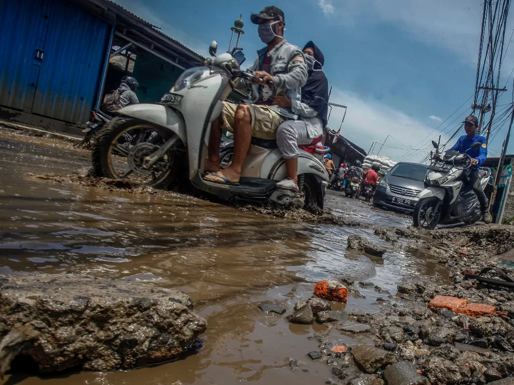 Pengendara melintasi jalan yang rusak dan tergenang air di jalan penghubung antara Kabupaten Bogor dan Kota Depok (ANTARA FOTO/Yulius Satria Wijaya)