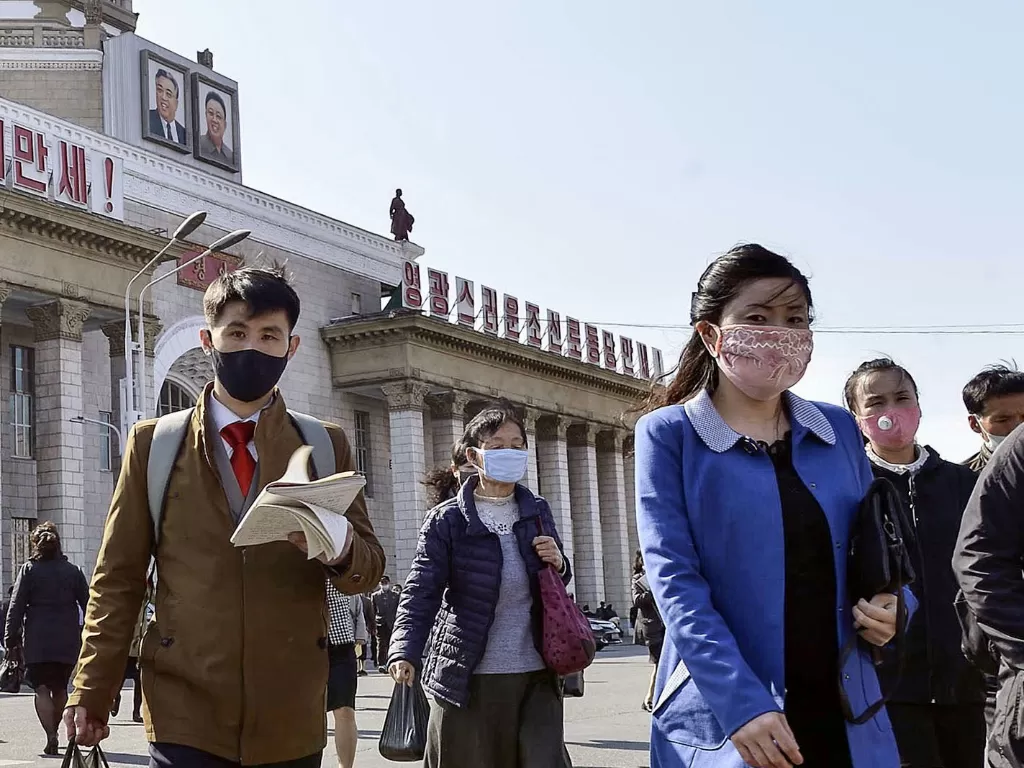 Orang-orang memakai masker sedang berjalan di depan Stasiun Pyongyang di Pyongyang, Korea Utara 27 April 2020. (REUTERS)