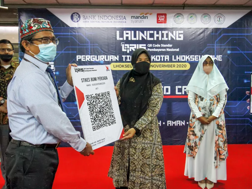 Kepala Perwakilan Bank Indonesia Yokon Afrinaldo (kiri) menyerahkan duplikat barcode berbasis Quick Response Indonesia Standard (QRIS) kepada perwakilan perguruan tinggi saat peluncuran QRIS di kantor BI Lhokseumawe, Aceh, Kamis (5/11/2020). ANTARA FOTO/R