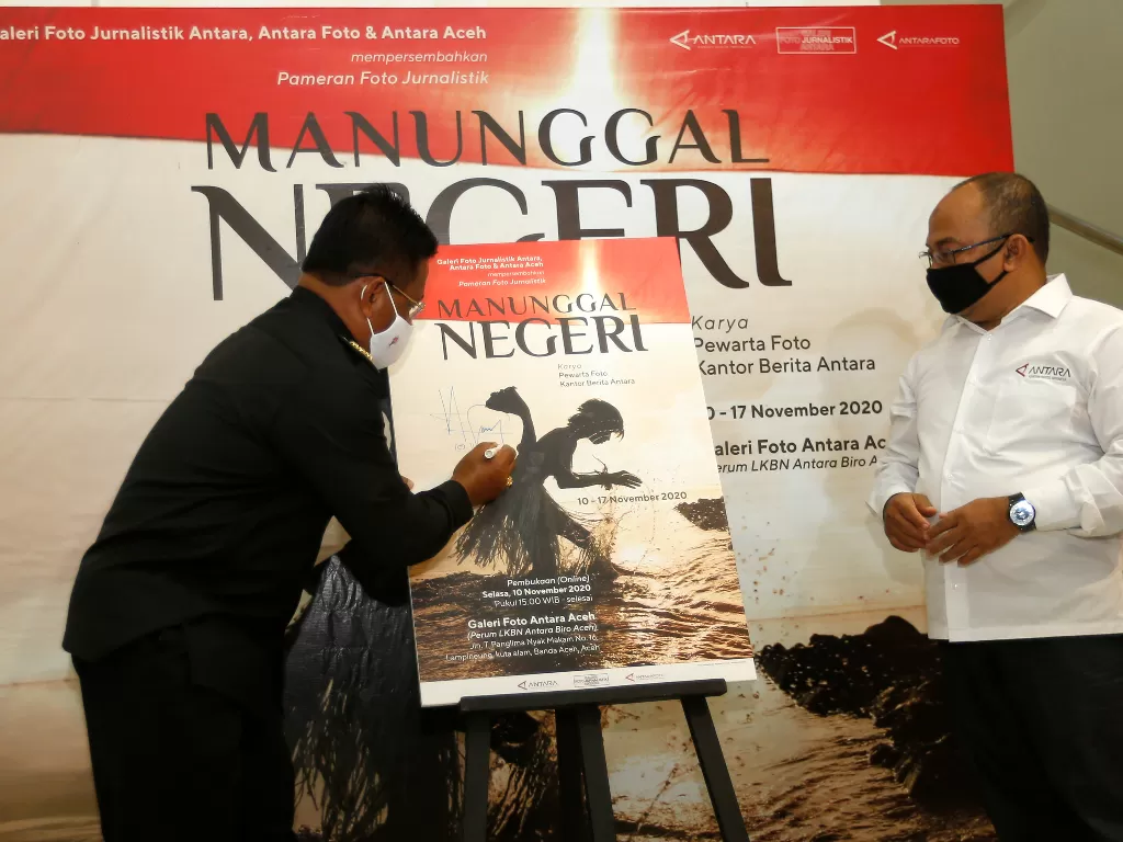 Wali Kota Banda Aceh Aminullah Usman (kiri) disaksikan Kabiro Antara Aceh Azhari (kanan) menandatangani poster pada pembukaan pameran foto jurnalistik secara virtual dengan tema 