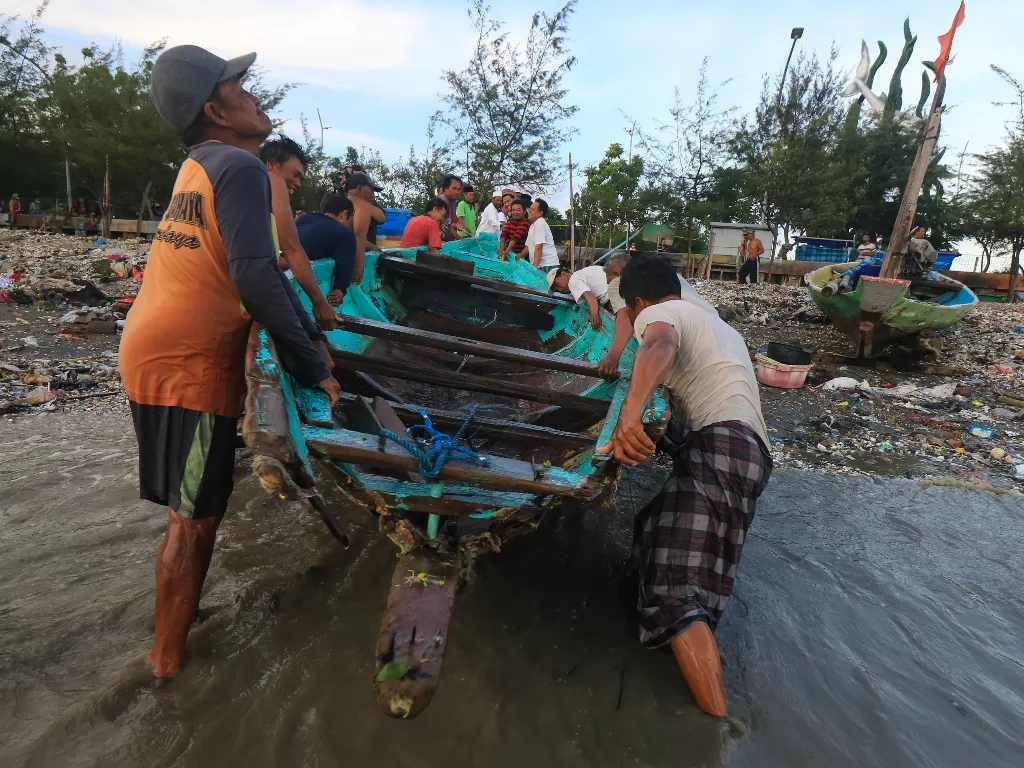 Nelayan mengevakuasi perahunya yang pecah akibat terhantam gelombang laut (ANTARA FOTO/Didik Suhartono)