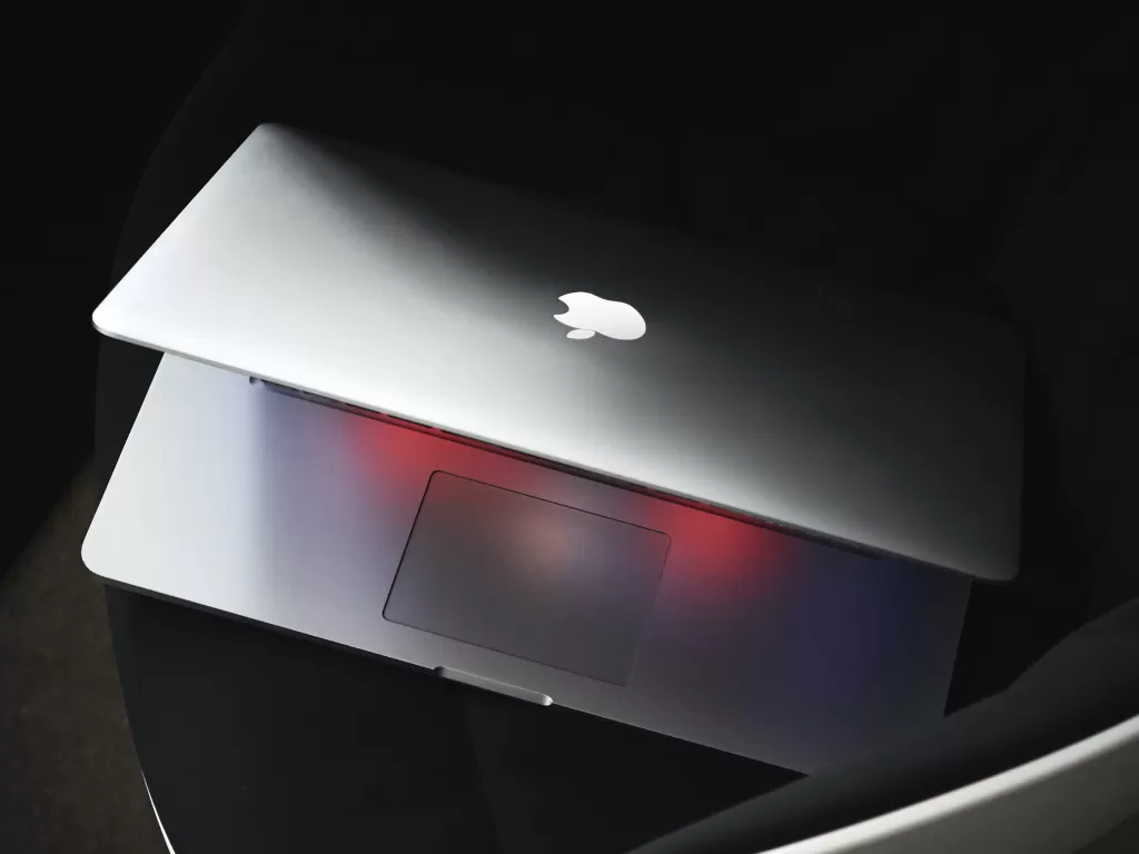 Ilustrasi laptop MacBook buatan Apple di atas kursi (photo/Unsplash/Luca Bravo)