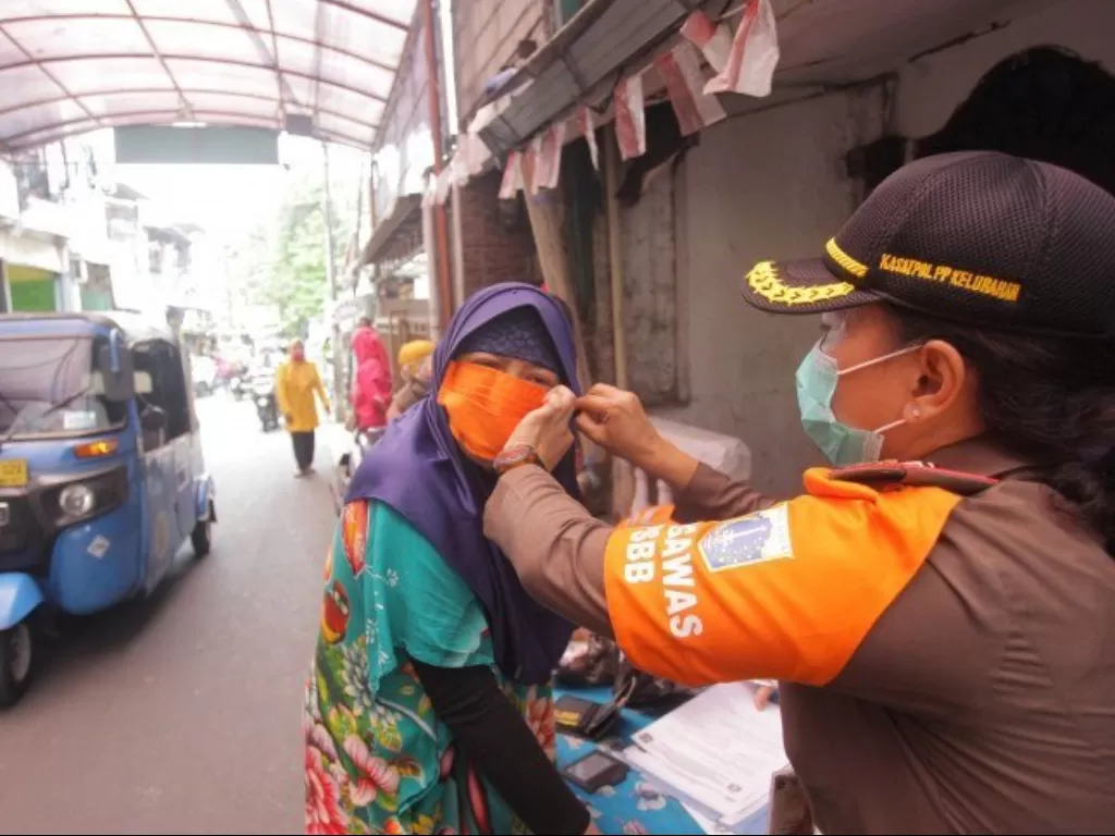 Petugas memakaikan masker kepada warga yang melanggar protokol kesehatan di kawasan Jalan Menteng Atas, Jakarta, Selasa (29/9/2020). (ANTARA FOTO/Reno Esnir)