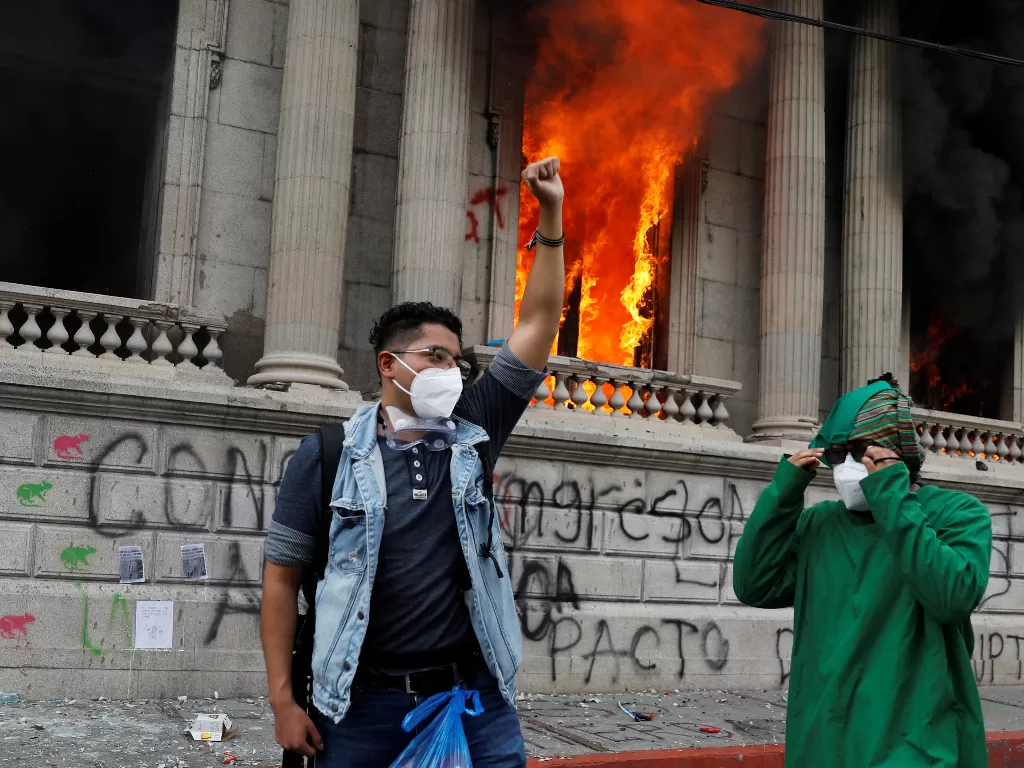 Seorang demonstran mengangkat tangannya setelah demonstran membakar gedung kantor Kongres (REUTERS/Luis Echeverria)