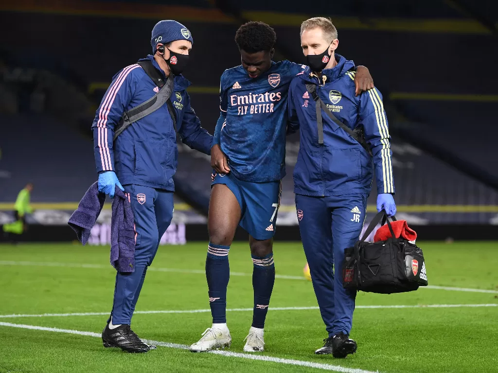 Bukayo Saka cedera dan dibantu staf medis di laga Leeds United vs Arsenal, Minggu (22/11/2020). (REUTERS/PAUL ELLIS)