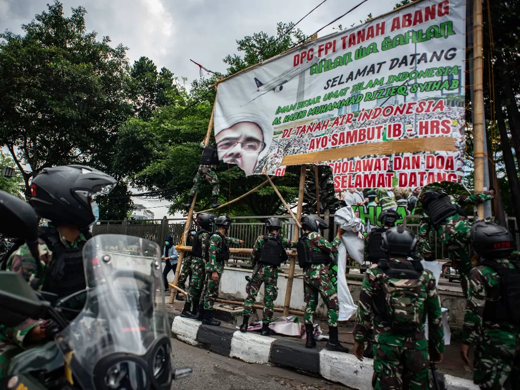 Prajurit TNI menertibkan spanduk tidak berizin saat patroli keamanan di Petamburan, Jakarta, Jumat (20/11/2020). (ANTARA)