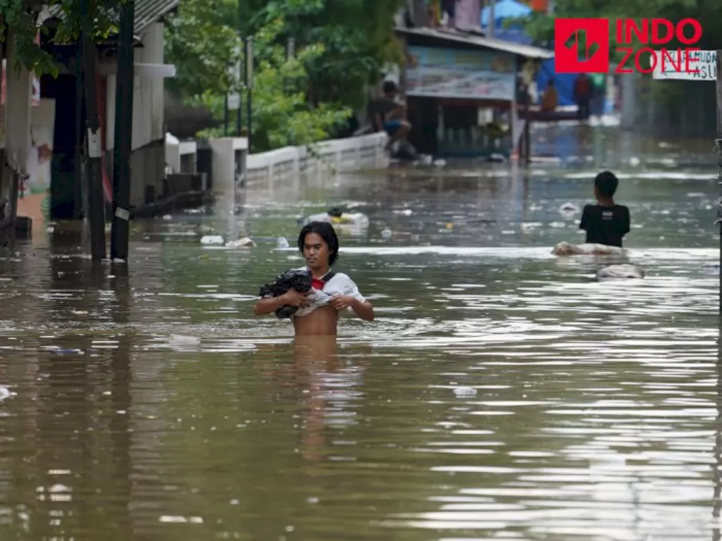 Warga melintasi banjir di kawasan Karet Tengsin, Tanah Abang, Jakarta Pusat, Selasa (25/2/2020). (INDOZONE)