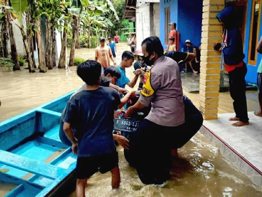 Personel Polsek Rawalo saat membantu mengangkat sepeda motor milik warga ke atas perahu agar terhindar dari banjir di Dusun Kaliwangi, Desa Tambaknegara, Kecamatan Rawalo, Kabupaten Banyumas, Jawa Tengah, Kamis (3/12/2020). ANTARA/HO-Polresta Banyumas