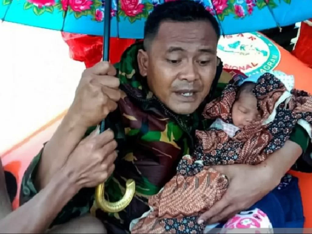 Prajurit TNI menyelamatkan seorang bayi yang terjebak banjir. (ANTARA)