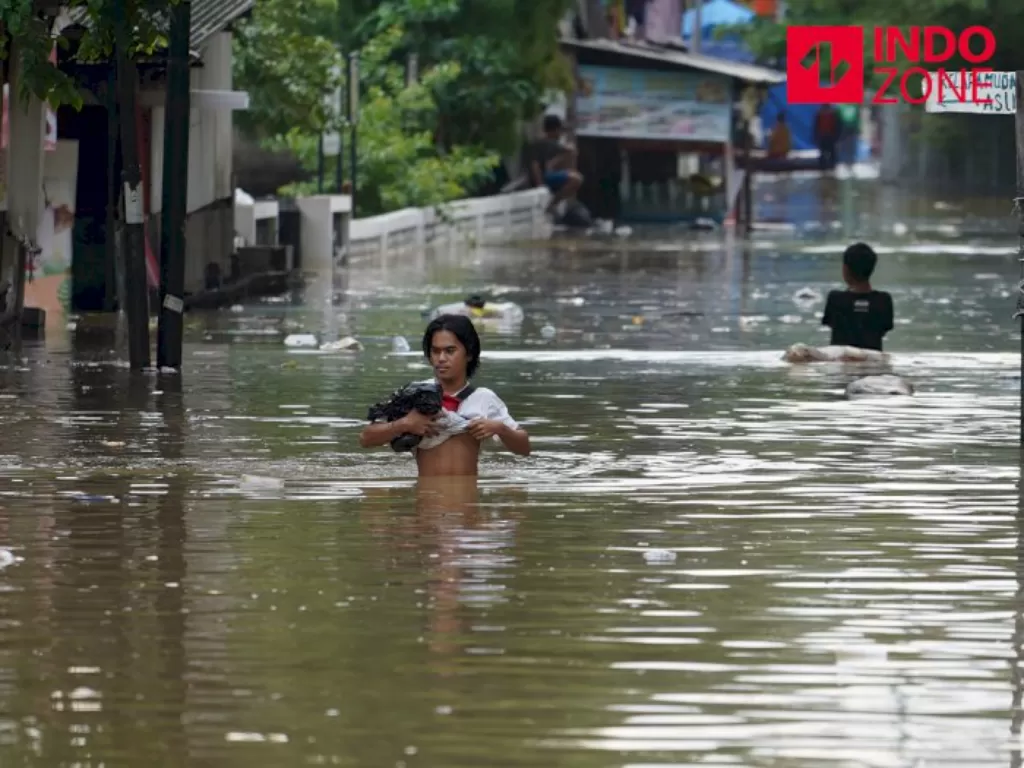 Warga melintasi banjir di kawasan Karet Tengsin, Tanah Abang, Jakarta Pusat. (INDOZONE)