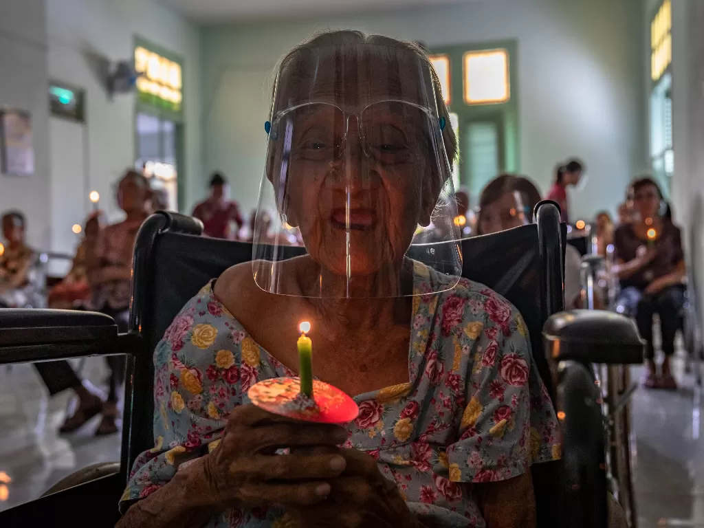 Seorang lansia menyalakan lilin (ANTARA FOTO/Aji Styawan)
