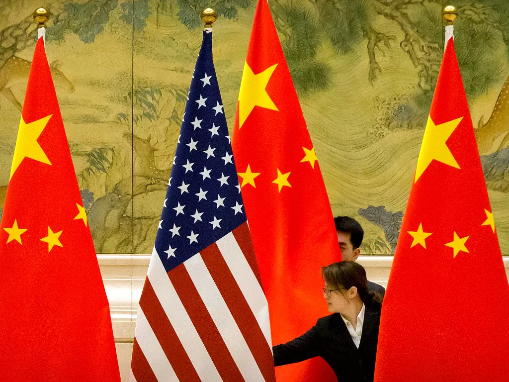 File Photo: Staf Tiongkok menyesuaikan bendera AS dan Tiongkok sebelum sesi pembukaan negosiasi perdagangan Tiongkok-AS di Beijing, 14 Februari 2019. (photo/Pool via REUTERS/Mark Schiefelbein)