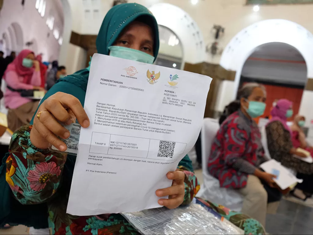 Warga penerima Bantuan Sosial Tunai (BST) menunjukkan berkas saat penyaluran BST tahap VIII di Kantor Pos Medan, Sumatera Utara, Jumat (13/11/2020). (Photo/ANTARA FOTO/Irsan Mulyadi)