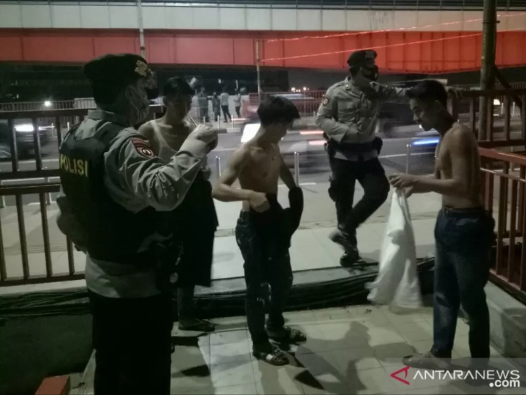 Polisi menegur warga yang tidak menggunakan masker saat ingin naik ke Jembatan Ampera. (ANTARA/Aziz Munajar)
