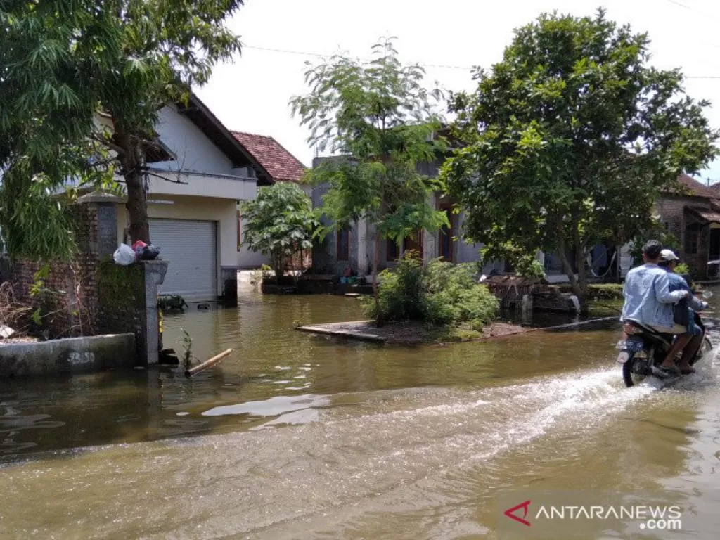 Warga melintasi jalan yang tergenang banjir, di Desa Setrokalangan, Kecamatan Kaliwungu, Kabupaten Kudus, Jawa Tengah, Senin (4/1/2021). (ANTARA/Akhmad Nazaruddin Lathif)